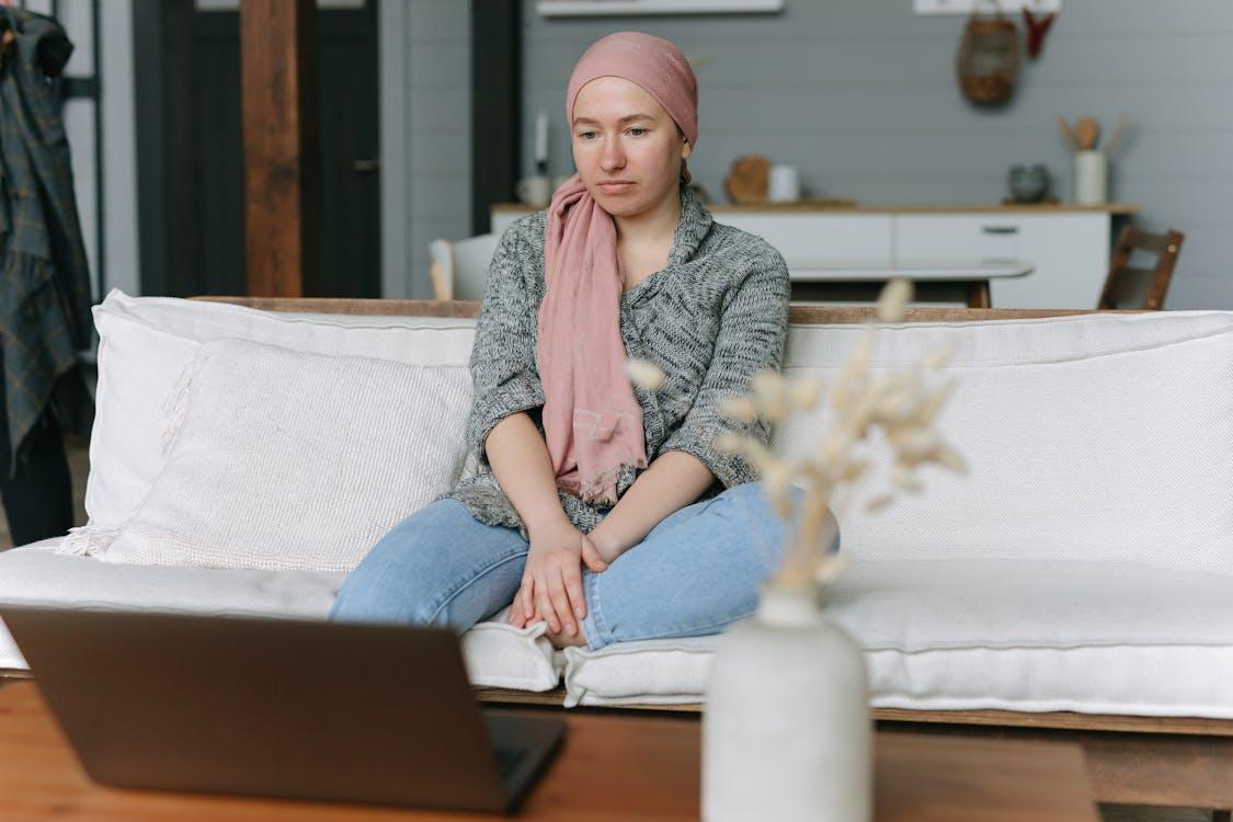 A woman sits in front of her laptop with a look of deep distress and frustration.