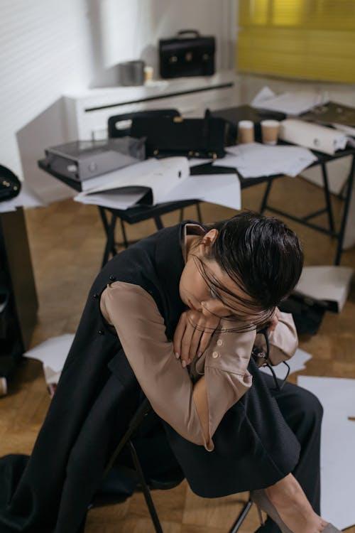 A woman at her workplace sits backwards on an office chair.