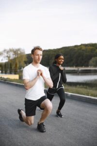 A man and woman performing synchronized stretching and warm-up exercises.