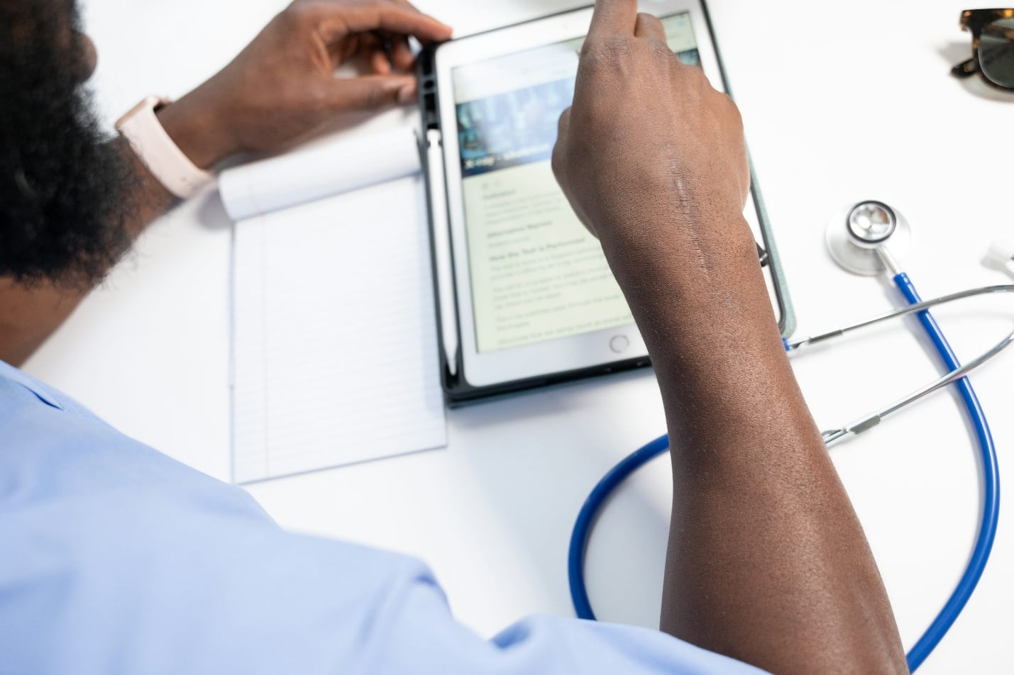 Healthcare professional reviewing patient information on a tablet during a telehealth consultation