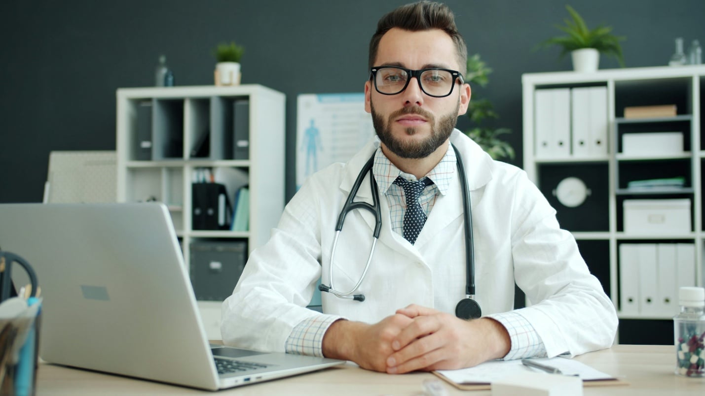 Doctor sitting at desk during a virtual consultation for workplace medical documentation