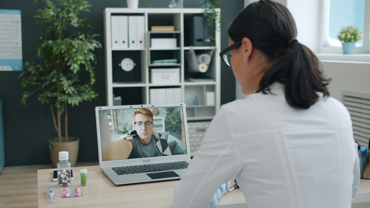 Patient attending a virtual consultation with a doctor on a laptop for work verification