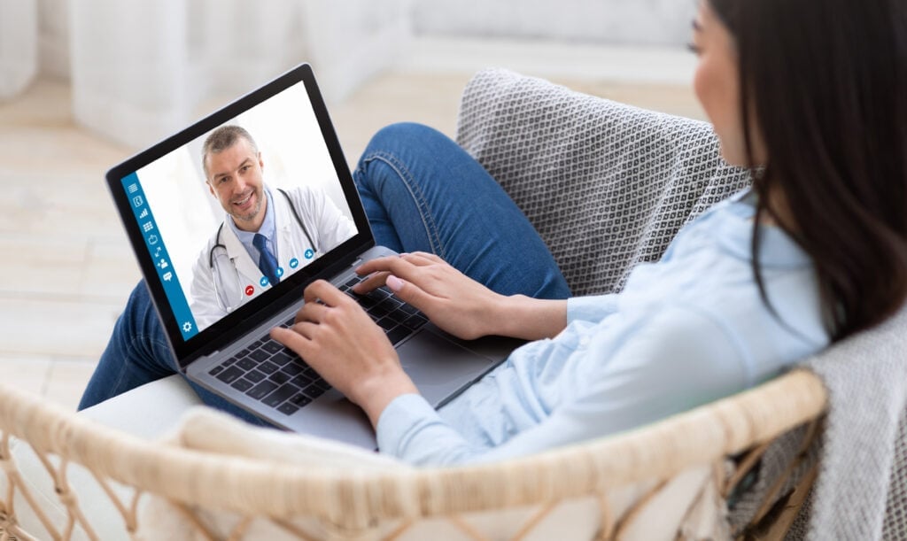 Woman using a laptop at home to speak with a doctor during a virtual urgent care visit
