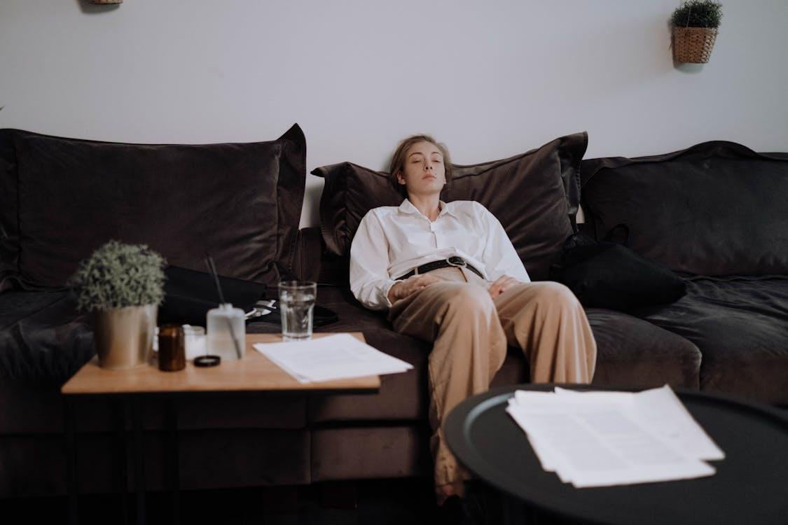 A woman sits slumped over on a living room couch.