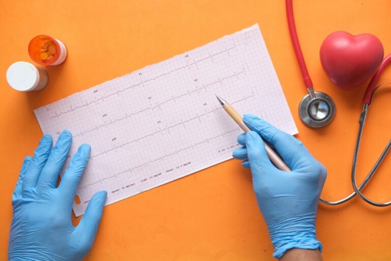 A doctor writing on a chart next to a stethoscope