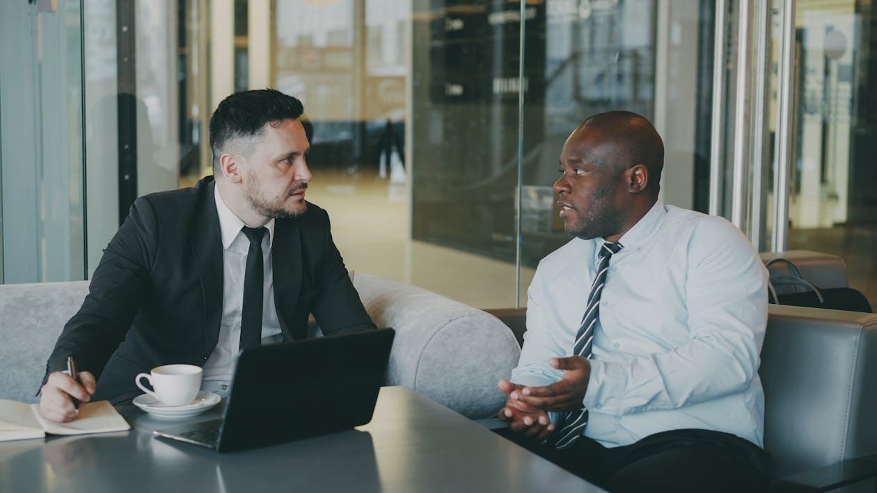 Two people talking in a meeting with a laptop on the table