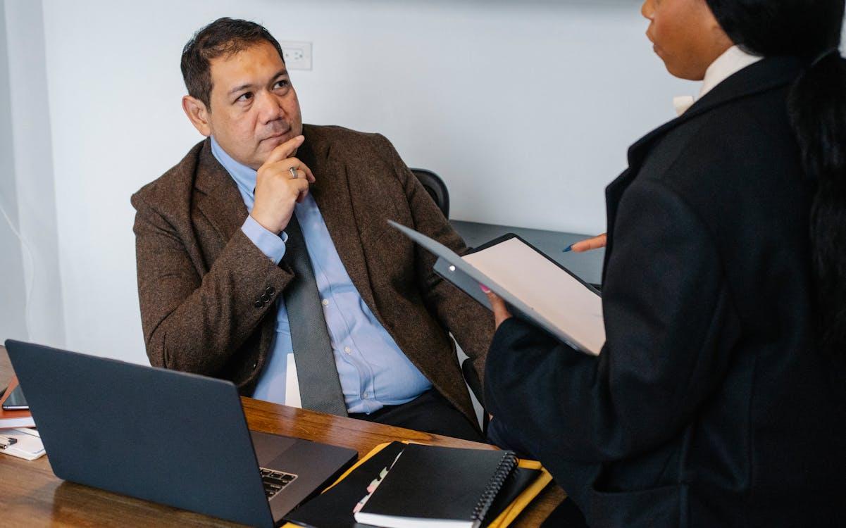 An employee holding a file and talking to another employee