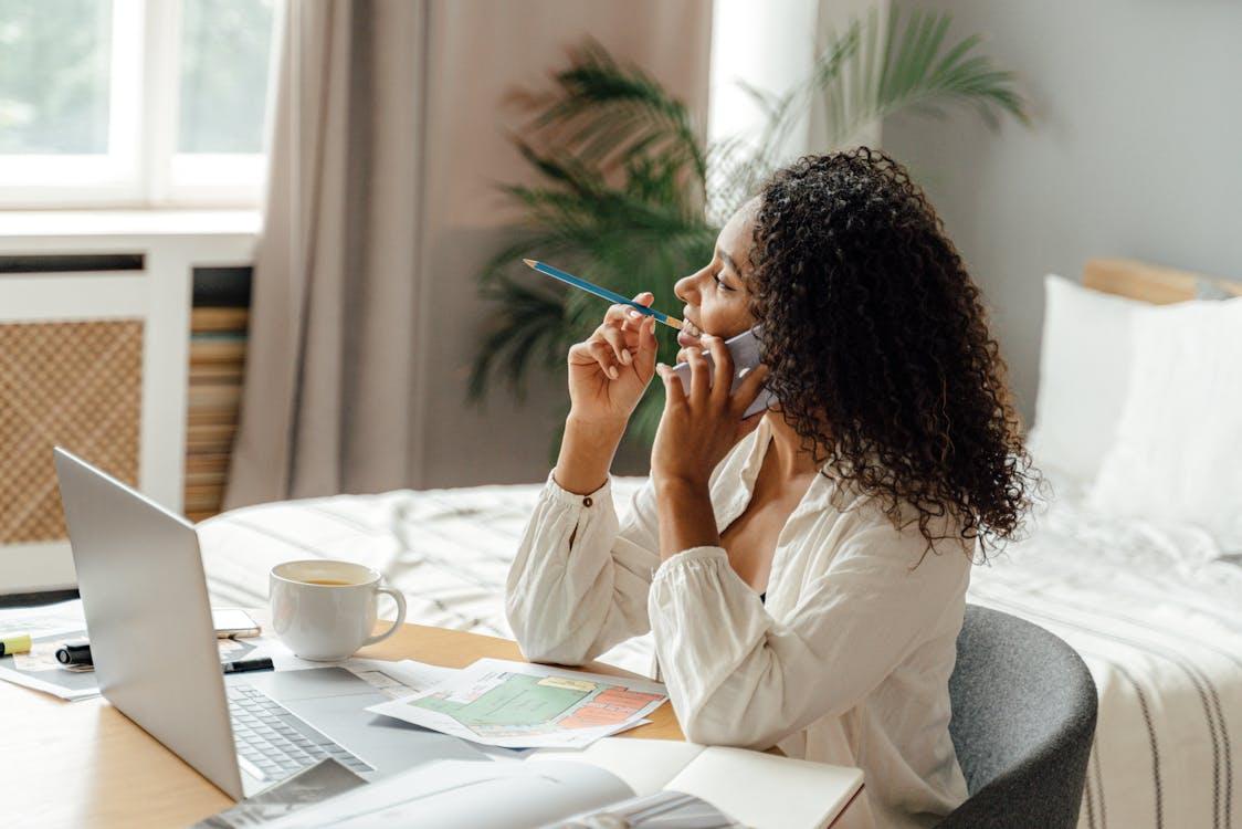 A person taking a phone call while working from their bedroom