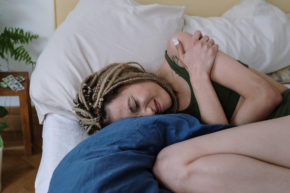 A person with stomach pain lying on their bed