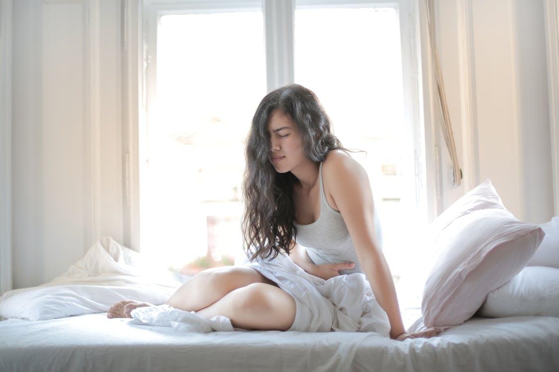 A person in bed holding their stomach