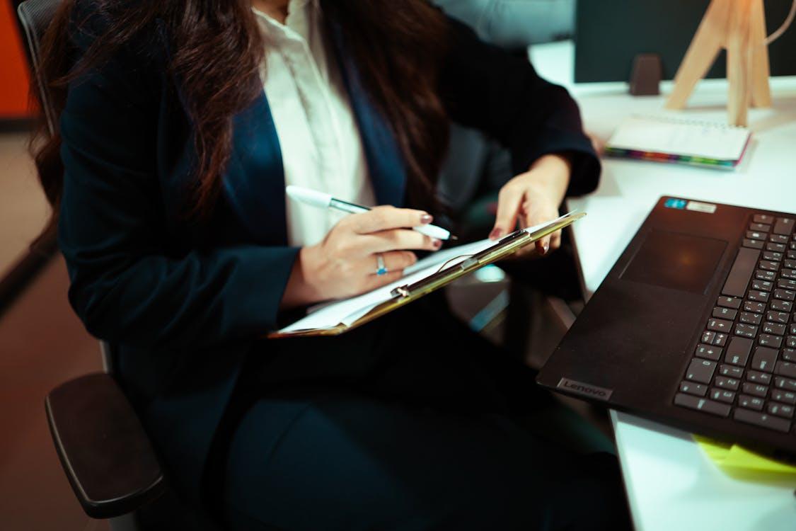 An executive writing on a paper attached to a clipboard