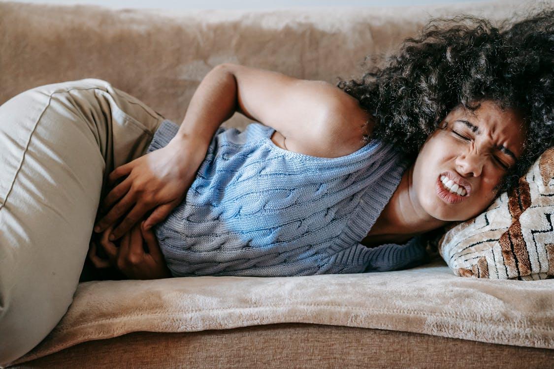 A person with stomach pain lying on the couch