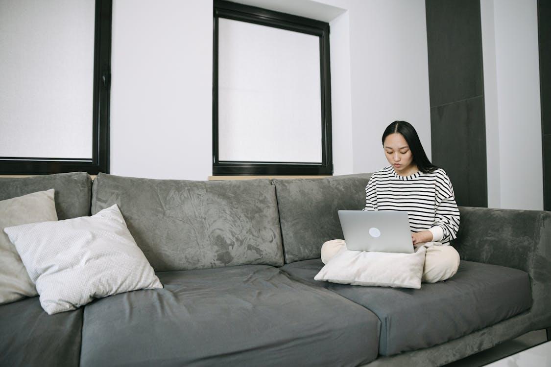 A person sitting on a couch and using a laptop