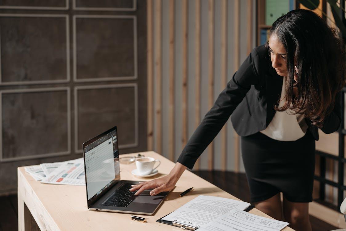 An executive standing next to a desk and using a laptop
