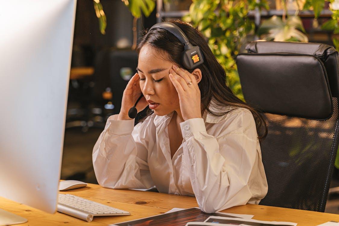 A person wearing headphones and holding her head