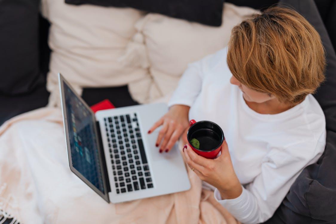 A person working on a laptop while holding a mug of tea