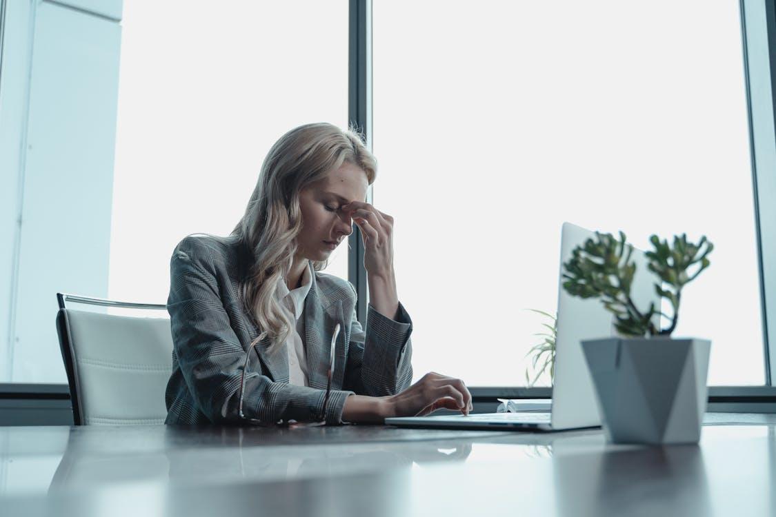 A person experiencing a migraine while using a laptop