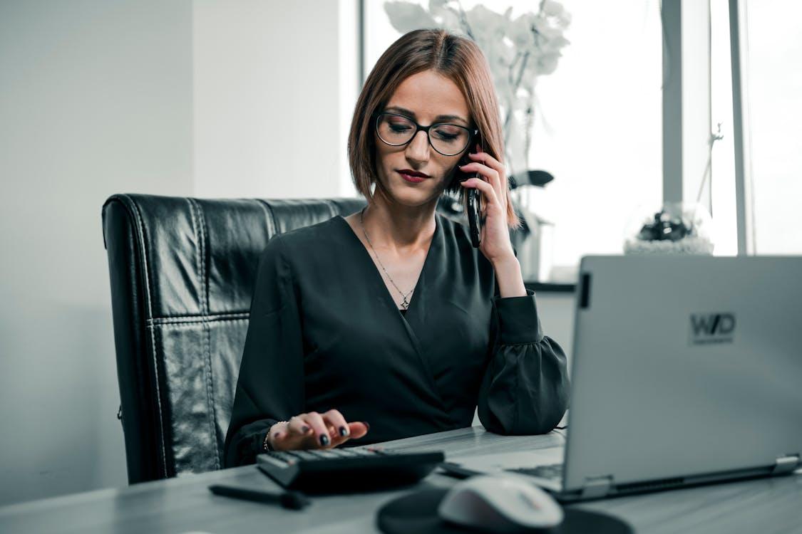 An executive taking a phone call while using a calculator