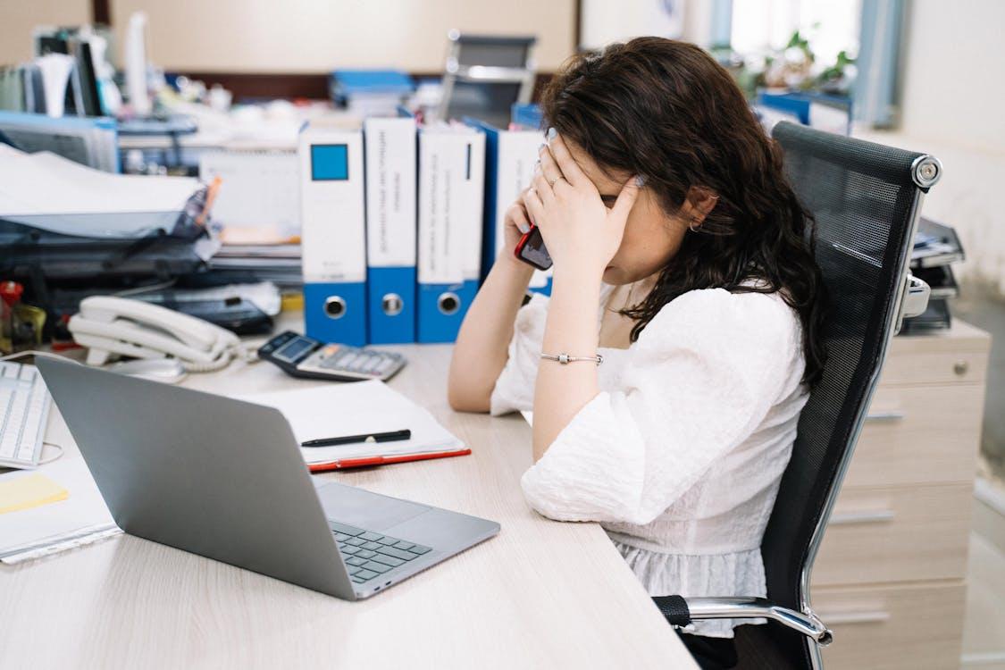 A person holding their head while on a phone call