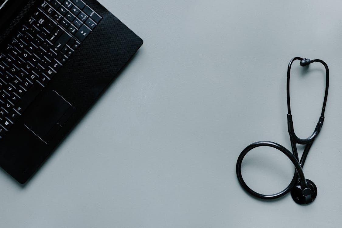 A laptop next to a stethoscope