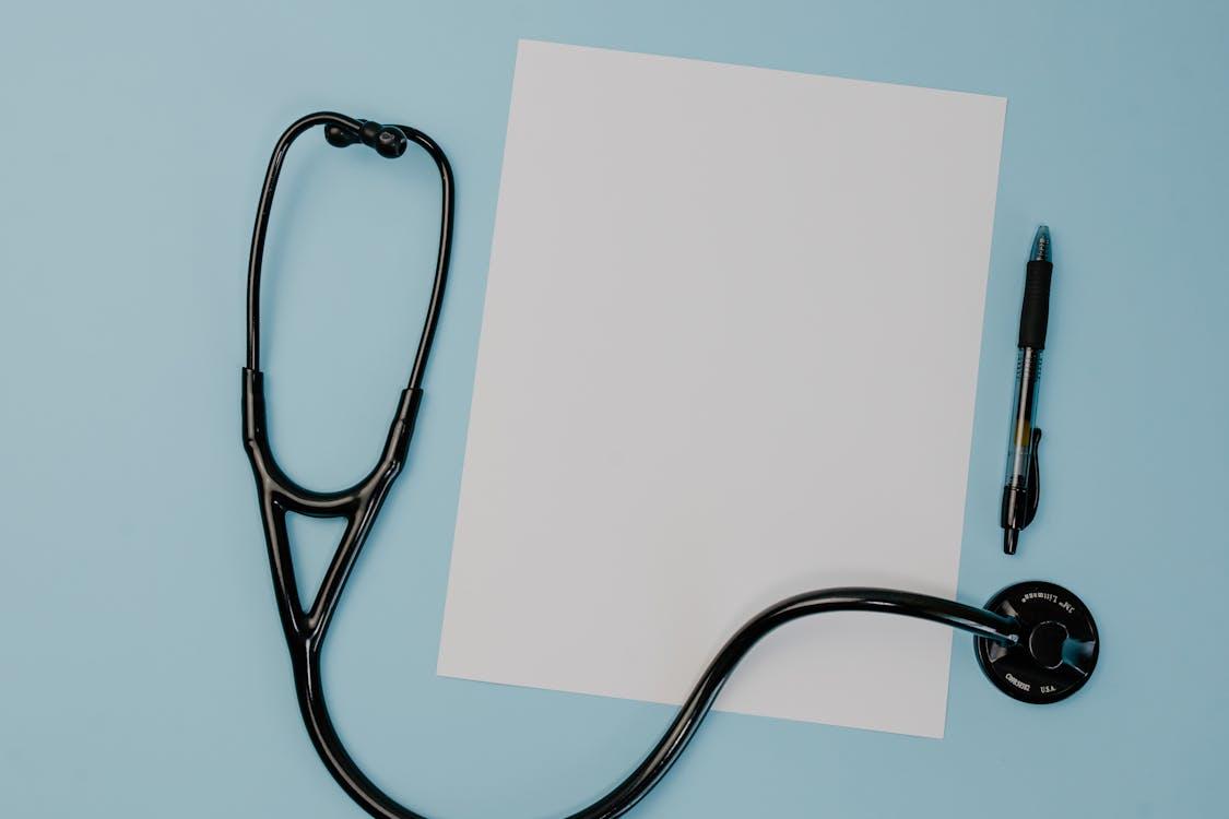 A stethoscope next to a paper and a pen