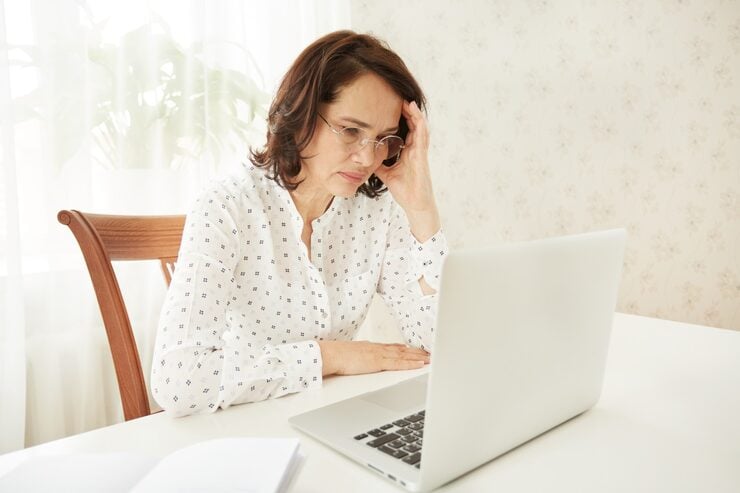 Frustrated woman reviewing information on her laptop at home after receiving a work-related update.