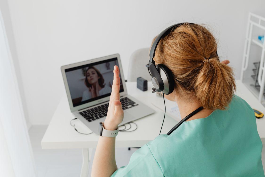 Physician conducting an online consultation with a patient via laptop in a modern office