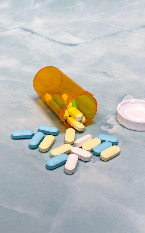 Prescription pills and an orange medication bottle representing an online refill evaluation