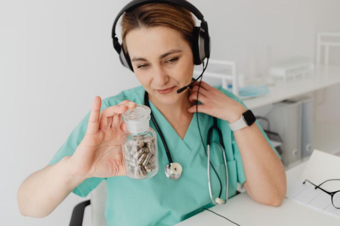 Provider holding a pill bottle during a telehealth prescription refill consultation